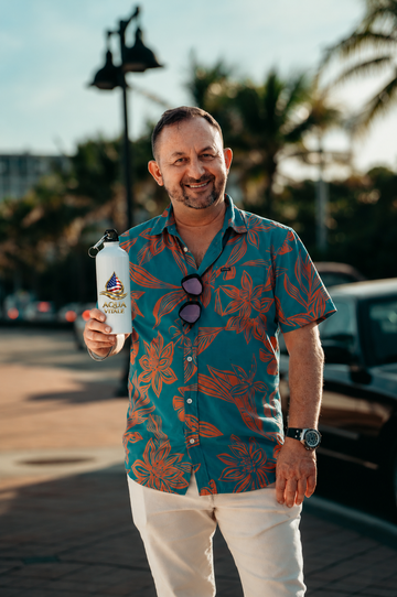 Man holding an Aqua Vitale branded stainless steel water bottle outdoors